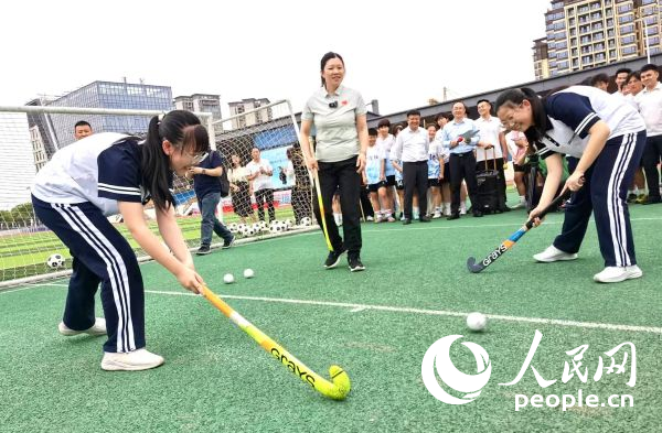 陈朝霞(中)指导学生体验曲棍球。 人民网记者 杨磊摄